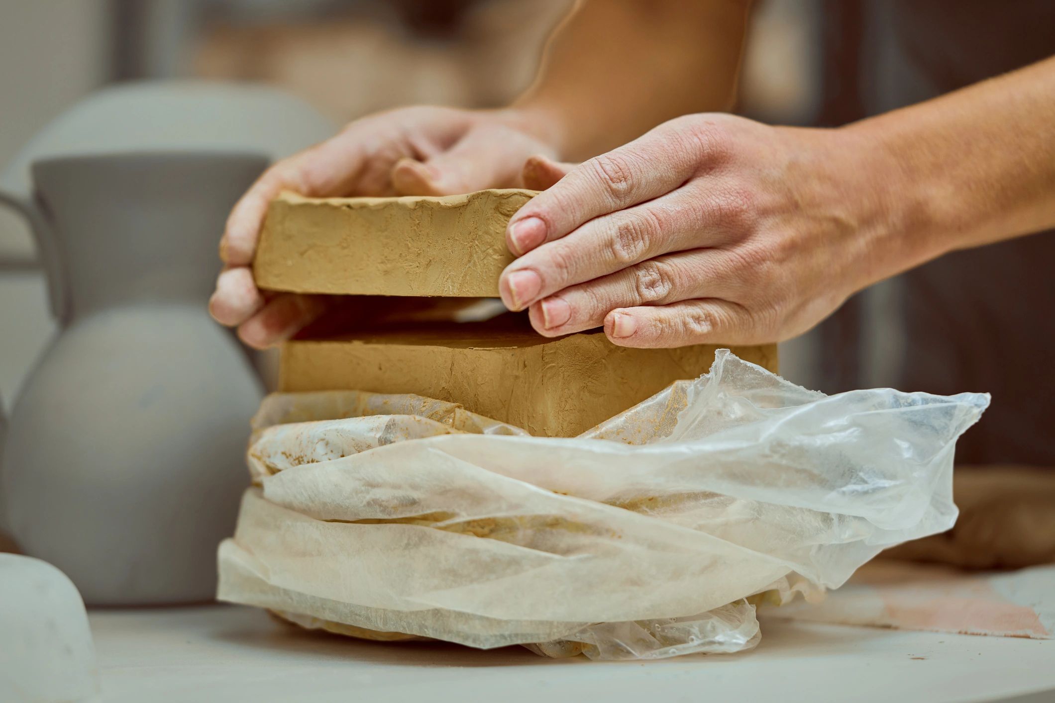 Hands shaping clay in a bright studio